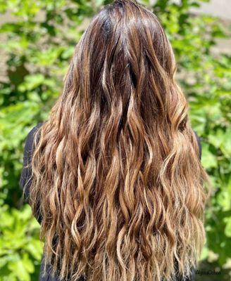 Dimensional balayage and gray coverage styled with soft beach waves.