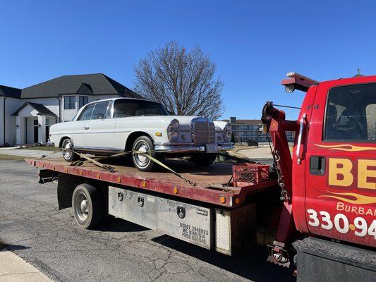 Flatbed towing a classic car.