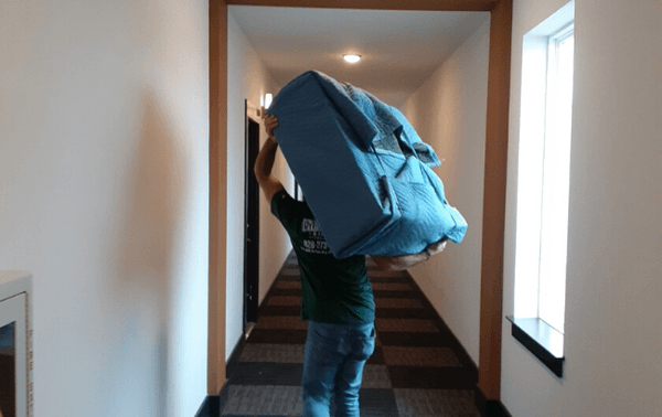 One of our movers carrying a small piece of furniture down a long hallway.