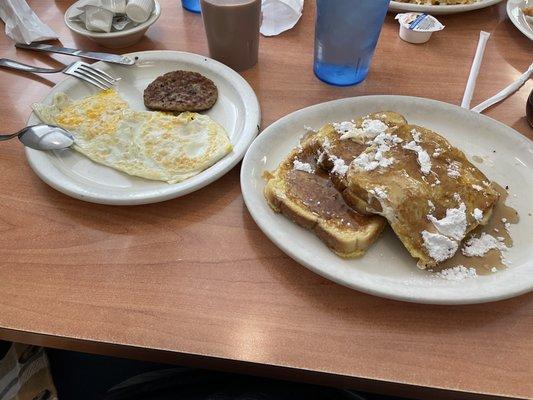 French toast breakfast with eggs and sausage patty.