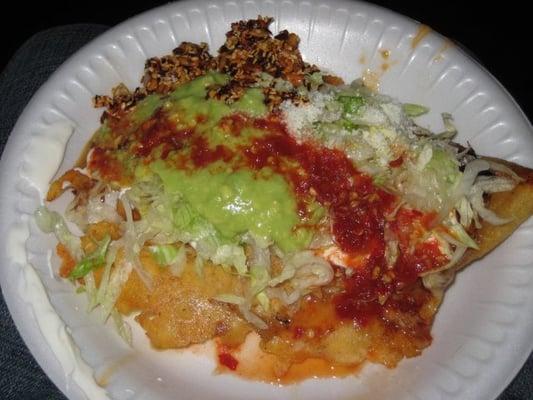 Hurache de Tinga - Fried Masa Topped with Stewed Pork, Melted Cheese, Frijoles, Shredded Lettuce, Crema, Avocado Salsa &