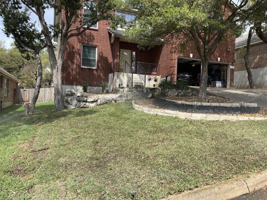 Xeriscaping flowerbeds made of chopped limestone rock and grass installation.