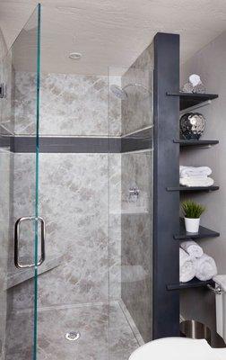 Custom glass frameless shower door with built in storage behind shower.