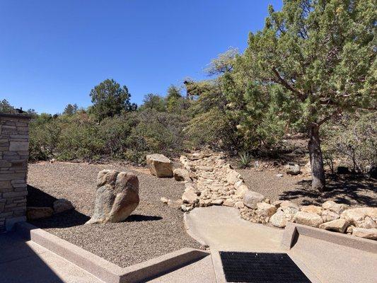 Newly graded drainage ditch with rock lining and artfully placed moss rock