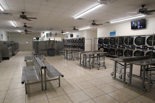 Spacious laundromat with lots of folding tables seating and big screen tvs!