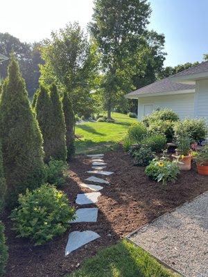 Brown enhanced mulch with stone walkway installation