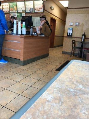 He's sitting and putting his shoes on the counter