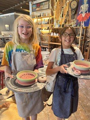 Two young ladies show off their work on the pottery wheel. Summer classes are in session!