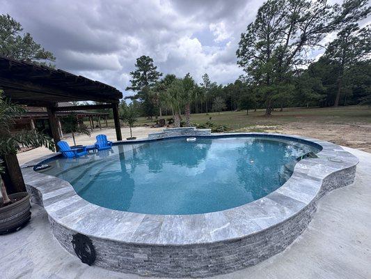 Raised pool with Blue moon travertine coping and ledgestone with Aqua Blue stonescape mini plaster