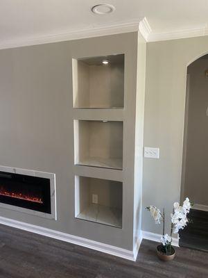 Custom accent wall with electric fire place and remote controlled cans in all of the shelves.