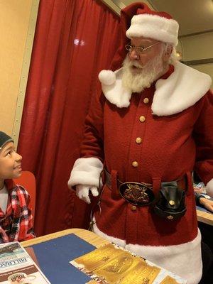 Santa handing out the first gift of Christmas: the silver bell