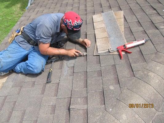 worker repairing a shingle roof