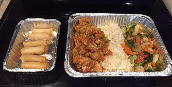 Orange chicken with rice, vegetables, and spring rolls