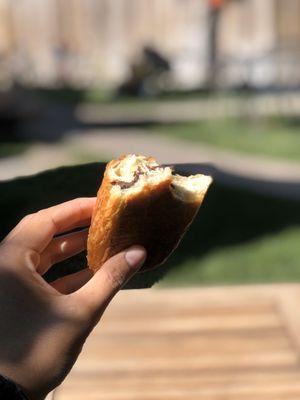 Enjoying a Delicious chocolate croissant in their peaceful outdoor seating area.