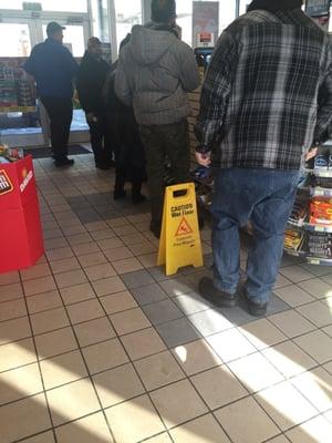 2 people working a store with a steady rush of customers.