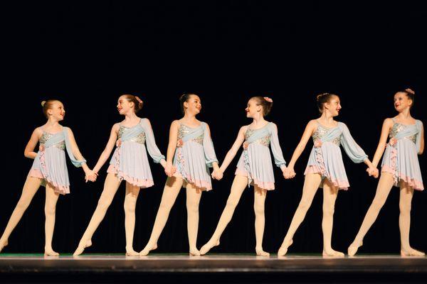 Lyrical dancers holding hands during performance