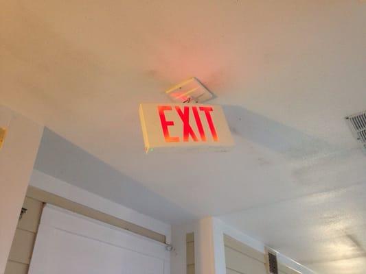 Exit sign literally hanging on by wires.