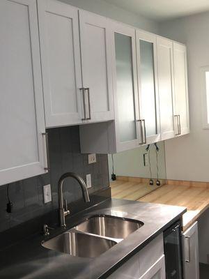 New cabinets with hardware and wiring for lighting fixtures underneath. New counter tops and a new subway tile back splash.