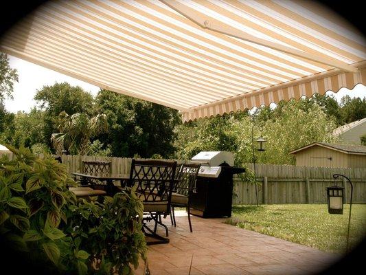 Striped Aristocrat retractable awning over a concrete patio.