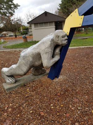 A troll pushing statue in the playground area.