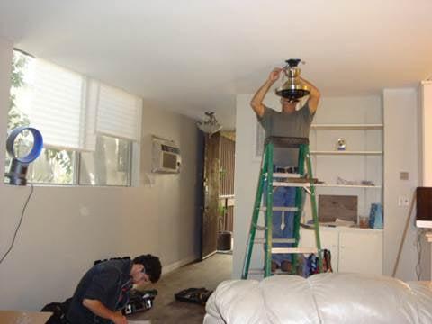 Installing one of the ceiling fans (the light fixture in the background was also installed.