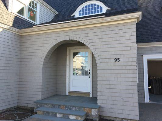 White cedar shingles with laced corners and arched entry