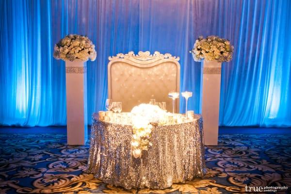 Sweet Heart table set up for a July Wedding at the US Grant: Silver sequence table cloth, High Back lounge, Blue led uprights.